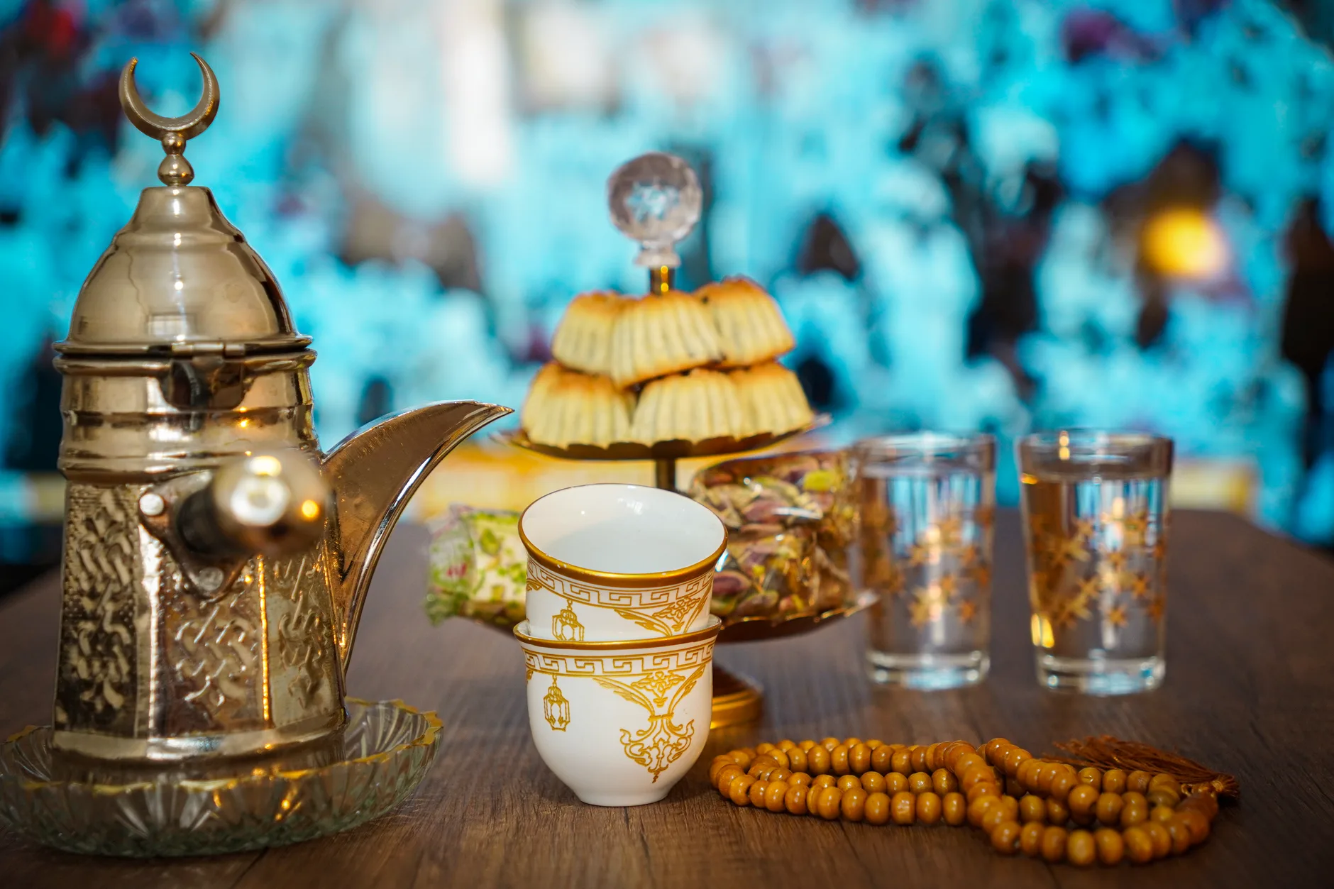 Cafetière arabe, tasses, pâtisseries et pistaches sur une table en bois